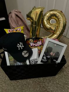 a basket filled with balloons, hats and other items next to the number one balloon