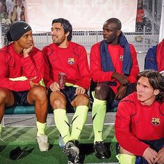 a group of men sitting on top of a bench next to each other in soccer uniforms