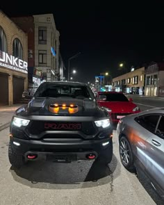 two cars are parked on the side of the road at night in front of some buildings