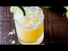 a close up of a drink on a table with limes and salt around it