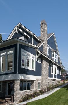 a blue house with white trim and windows on the front, along side a green lawn