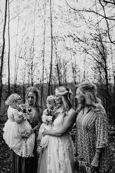 a group of women standing next to each other in front of trees and grass with one woman holding a baby