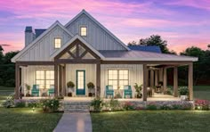 a house that is lit up with lights on the front porch and covered in flowers