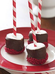 three chocolate covered desserts on a plate with candy canes sticking out of them