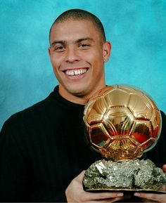 a man holding a golden soccer ball in his hands