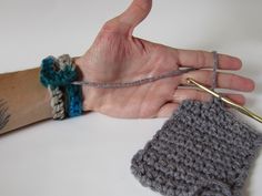 a hand holding two crocheted wristbands next to a knitted object