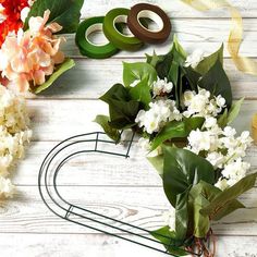 some flowers are sitting on a table with ribbon and scissors next to it, along with other items