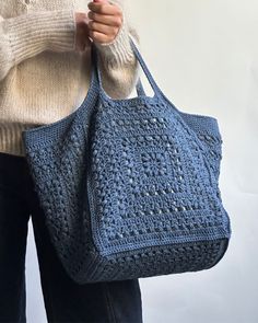 a woman holding a crocheted blue purse