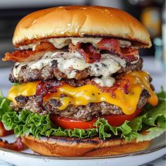 a cheeseburger with bacon, lettuce and tomato on a bun sitting on a plate