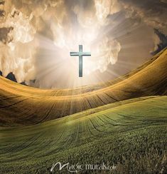 a cross in the middle of a field with sun rays coming out from behind it