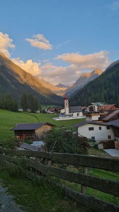 a small village in the middle of mountains with a church on it's side