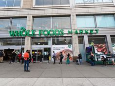 the whole foods market is open for business and people are walking in front of it