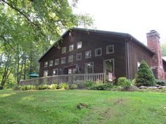 a large brown house sitting in the middle of a lush green field next to trees