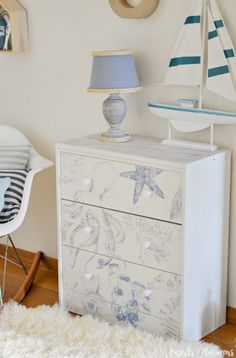 a white dresser with blue and white designs on it, next to a rocking chair