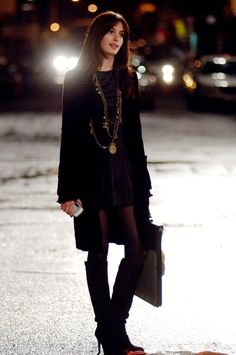 a woman is standing in the street at night with her hand on her hip and wearing black boots