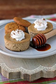 three desserts on a plate with honey and whipped cream