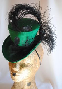 This seductive evening mini top hat is an excellent choice for any dark cabaret event. It is covered with a rich emerald green(pictured) or black thick satin fabric and embellished with various black trimmings. A curled black ostrich feather, dotted black tulle, chic black stripped rooster feathers and a glorious black beaded button. For sparkling burlesque style appearances! Measurements : height 4 inches( 10 cm ) front to back 9 inches ( 22 cm ) side to side 7.5 inches ( 19 cm ) This mini top Curved Brim Top Hat For Kentucky Derby Costume, Evening Gatsby Mini Hat With Short Brim, Gatsby Style Mini Hat With Short Brim For Evening, Gatsby Style Mini Hat With Short Brim For Parties, Fitted Flapper Costume Hats And Headpieces For Party, Short Brim Top Hat For Carnival Party, Elegant Top Hat For Kentucky Derby Costume Party, Steampunk Brimmed Mini Hat For Party, Steampunk Brimmed Top Hat For Party