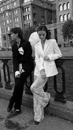 black and white photograph of two people sitting on the steps in front of some buildings