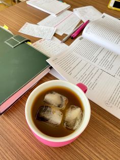 a cup of tea sitting on top of a wooden table next to an open book