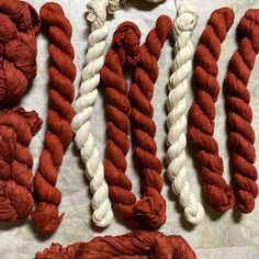 several red and white yarns are laid out on a table with one knot in the middle