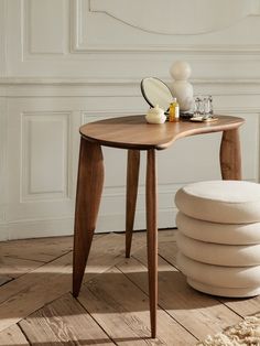 a wooden table sitting on top of a hard wood floor next to a white wall