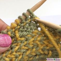 someone is crocheting together with yarn and a pink heart on the knitting needle