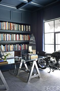 a motorcycle parked in front of a bookshelf filled with lots of books next to a glass table