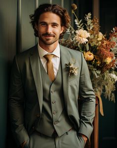 a man wearing a suit and tie standing next to a vase with flowers in it