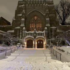 the front entrance to an old church with snow on the ground and trees around it