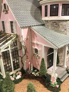 a pink doll house with white trim and flowers on the front porch, windows, and door