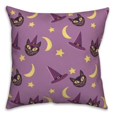 a purple pillow with black cats and witches hats on it, sitting in front of the moon