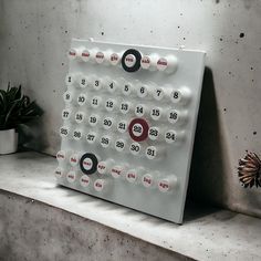 a white clock sitting on top of a shelf next to a potted plant