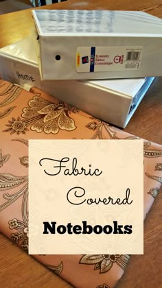 fabric covered notebooks sitting on top of a wooden table next to a binder