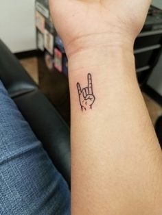 a person with a tattoo on their wrist holding up the peace sign in front of them