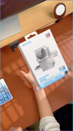 a person holding up a computer mouse in front of a box