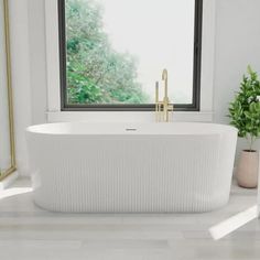 a white bathtub sitting next to a window in a room with potted plants