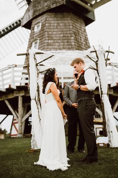 a bride and groom standing in front of a windmill