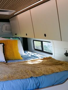 a bed with two pillows on top of it in a room next to some cupboards