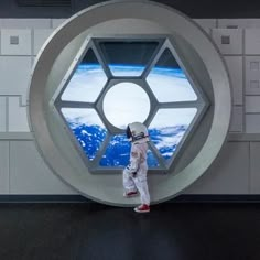 an astronaut standing in front of a window looking at the earth