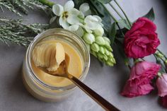 a jar filled with butter next to flowers