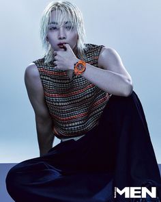 a woman sitting on the ground with her hand under her chin, wearing a watch