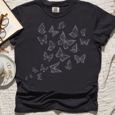 Embrace nature's beauty with our "Dance of the Butterflies" t-shirt, made from high-quality Comfort Colors material. This shirt features a stunning butterfly design that captures the essence of freedom and grace. Perfect for casual outings, nature walks, or simply adding a touch of whimsy to your everyday wardrobe. This shirt is perfect for the butterfly or nature lover in your life.  Comes in multiple colors! ✨ SIZE AND FIT: Your shirt will be printed on a high-quality, soft and comfortable unisex t-shirt. Sizes run true to size, which takes the guesswork out of ordering. If you like your t-shirts loose or oversized - size up. For a more fitted women's style - size down. If you are looking for the 'shirt dress' look you see in some of the photos, size up 2 or 3 sizes. Please refer to our Summer Cotton T-shirt With Butterfly Sleeves, Relaxed Fit Butterfly Print Graphic Tee, Butterfly Tshirt, Trendy Short Sleeve T-shirt With Butterfly Print, Cute Butterfly Print Crew Neck T-shirt, Aesthetic Butterfly, Blue Short Sleeve T-shirt With Butterfly Print, Relaxed Fit Short Sleeve T-shirt With Butterfly Print, Casual T-shirt With Butterfly Print