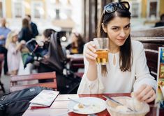 a woman sitting at a table with a drink in her hand