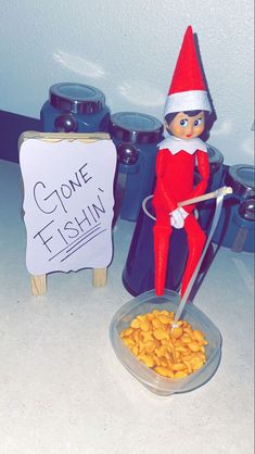 an elf is standing next to a bowl of peanuts and a sign that says gone it fishin