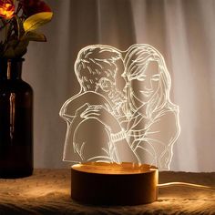 a couple kissing in front of a vase with flowers on the table next to it