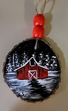 a red barn ornament hanging on a white wall next to a red bead