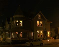 a large house that is lit up at night with people in the windows and onlookers