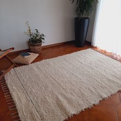 a white rug sitting on top of a wooden floor next to a potted plant