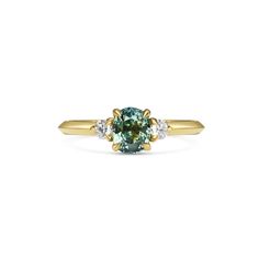 an oval blue and white diamond ring with three diamonds on the band, set in yellow gold