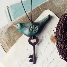 a bird figurine sitting on top of an old key next to a nest